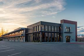 A modern building with a parking lot in front.