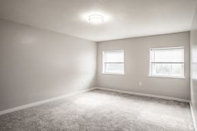 an empty room with two windows and a carpeted floor