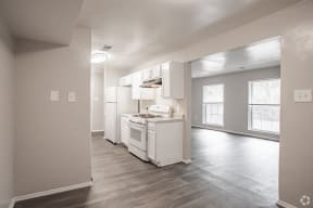 an empty kitchen with white appliances and a wood floor
