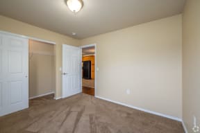 an empty living room with carpet and a door to a closet
