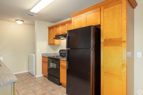 a kitchen with a black refrigerator and a stove