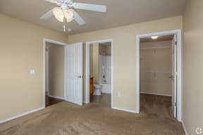 an empty bedroom with a ceiling fan and a bathroom