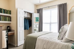 a bedroom with a large window and a bed with a white comforter