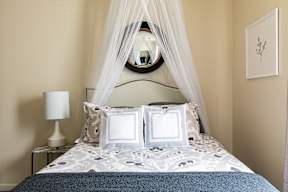 a bedroom with a bed with white bedding and a white canopy over it