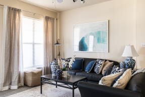 a living room with a black leather couch and a coffee table with blue and white pillows