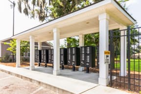 a row of black voting booths under a pavilion with trees in the background