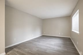 an empty living room with wood flooring and a window