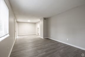 an empty living room with a large window and wood flooring