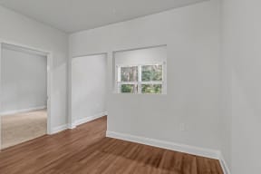 a bedroom with white walls and hardwood floors