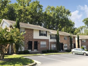 an apartment building with a parking lot and trees