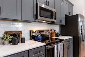 A kitchen with a black stove top oven and a black microwave above it.