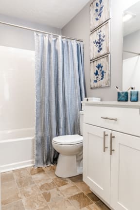 a bathroom with white cabinets and a blue shower curtain