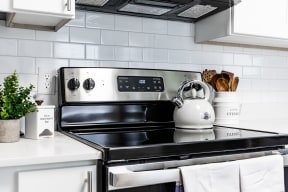 a kitchen with a stove top oven next to a counter top with a kettle on it