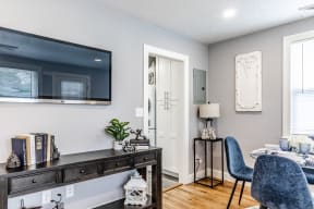 a living room with a tv on the wall and a desk with a chair