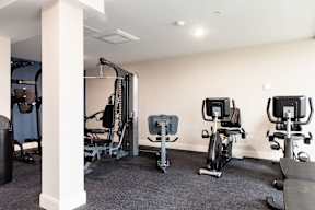 A gym with a row of exercise bikes and a weight machine.
