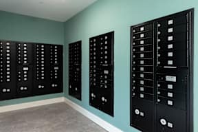 Three black mailboxes on a wall.