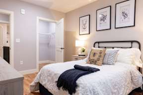 A bedroom with a bed, nightstand, and three framed pictures on the wall.