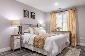 A bedroom with a large bed and a nightstand with a lamp.