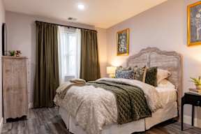 A bedroom with a large bed and a window with curtains.