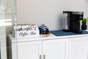 a coffee maker on a counter with coffee cups and a box of coffee