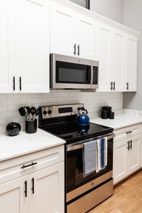 a kitchen with white cabinets and black appliances