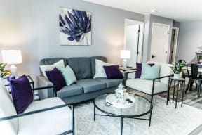 a living room with a gray couch and purple pillows