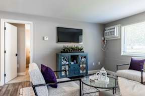 A living room with a blue cabinet, a white couch, and a glass table.