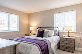A bedroom with a bed, nightstand, and window.