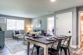 A dining room with a table set for two and chairs around it.