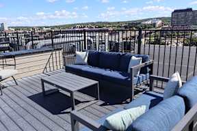 A blue couch with a wooden table in front of a balcony.
