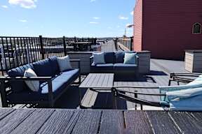 A wooden deck with a blue couch and a white pillow.