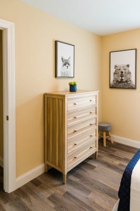 a chest of drawers in a bedroom with two pictures on the wall