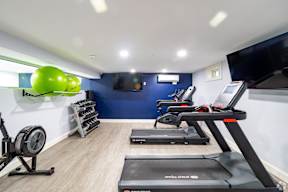 A gym with treadmills, elliptical machines, and a fan.