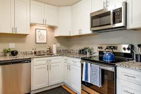 A modern kitchen with white cabinets and stainless steel appliances.
