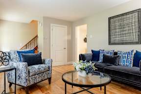 A living room with a black couch and a blue and white patterned chair.