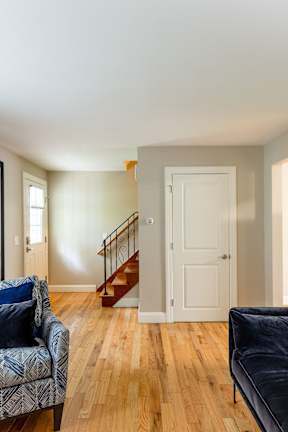 A living room with a couch, chair, and stairs.