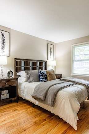 A bedroom with a bed, nightstand, and a window.
