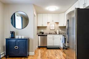 A kitchen with a blue cabinet and a round mirror on the wall.