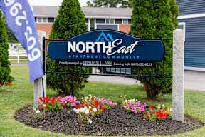 A sign for North East Apartment Community with a phone number on it.