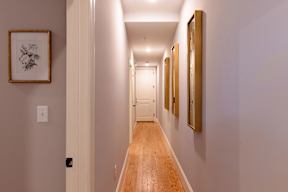 A hallway with a light on the wall and pictures on the wall.