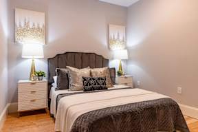 A bedroom with two beds, nightstands, and lamps.
