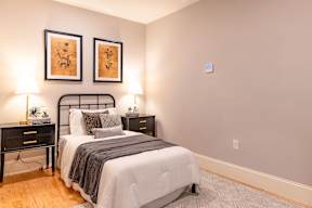 A bedroom with a bed, nightstands, and two wall lamps.