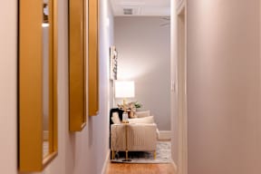 A hallway with a light on and a chair in the middle.