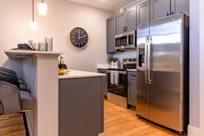 A modern kitchen with a stainless steel refrigerator and wooden floors.