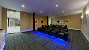 A room with a carpeted floor and a row of chairs.