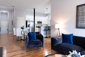 A modern living room with a black couch and a dining table.