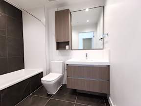 A modern bathroom with a toilet, sink, and bathtub.
