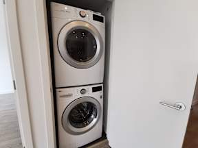 Two washing machines are stacked in a small space.