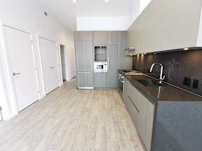 A modern kitchen with a wooden floor and a dark counter.