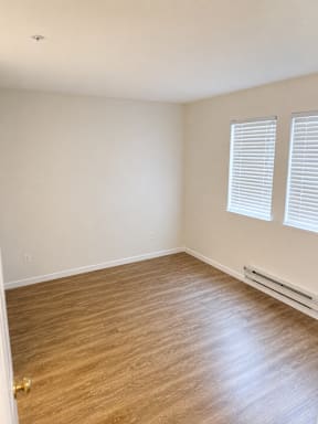 A room with wooden flooring and a window with blinds.
